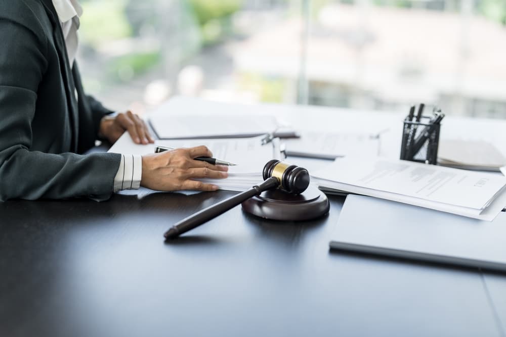 Lawyer working with a lawbook at a desk, with a gavel symbolizing legal counsel, justice, and the law.