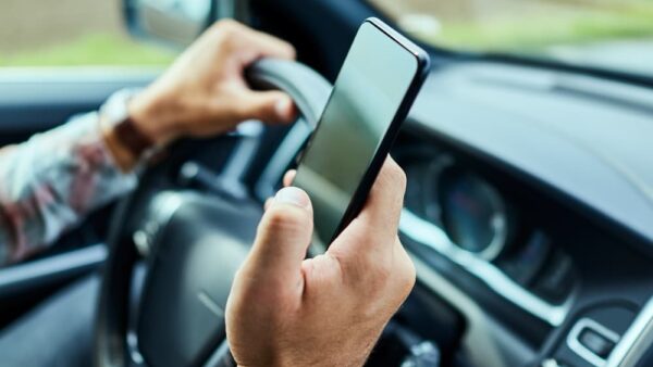 Man using a smart phone while driving a car in the city