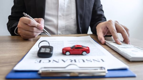 Young salesman receiving money and giving car's key to customer after sign agreement contract