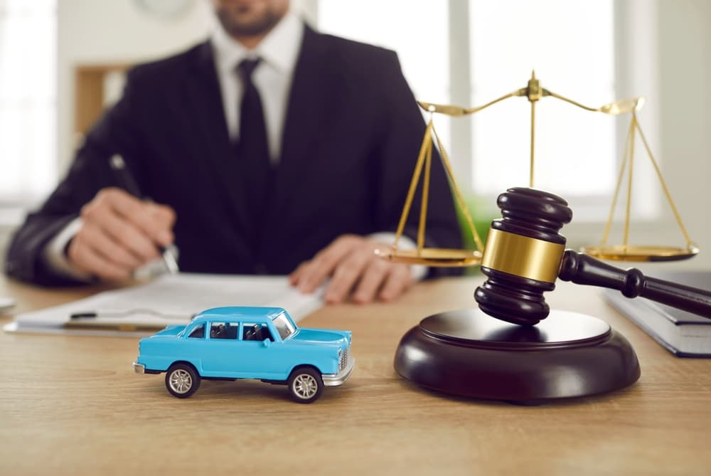 Miniature car beside a judge's gavel, representing legal issues related to vehicle purchase, ownership, or leasing, on a lawyer's desk.