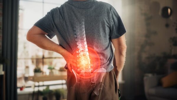 Close-up of an elderly man massaging his back to relieve discomfort from spine trauma or arthritis.