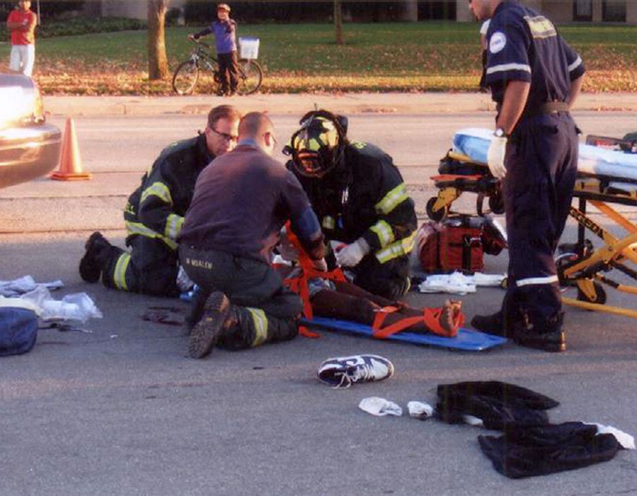 A man standing beside a car with significant damage, likely the result of an accident, as part of a case study on accidents