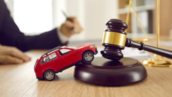 Small car model on wooden desk with judge's hammer.