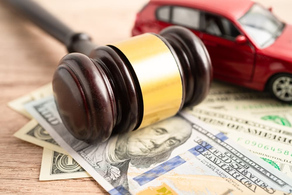 Hammer gavel judge and US dollar banknote money with car vehicle accident