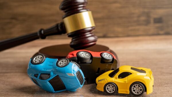 Judge's gavel beside a car, symbolizing a vehicle accident lawsuit and insurance claim coverage.