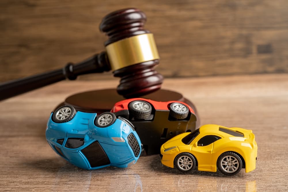 Judge's gavel beside a car, symbolizing a vehicle accident lawsuit and insurance claim coverage.