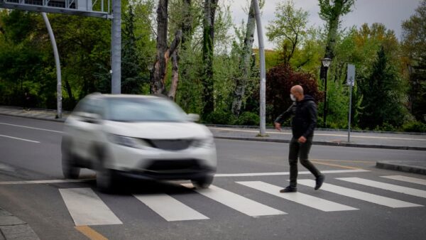 Pedestrian walking on zebra crossing and a driving car failing to stop in blurred motion