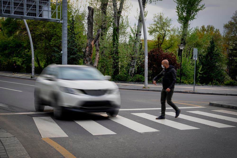 Pedestrian walking on zebra crossing and a driving car failing to stop in blurred motion