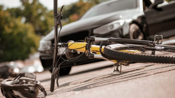 Bicycle and helmet lying on road and car