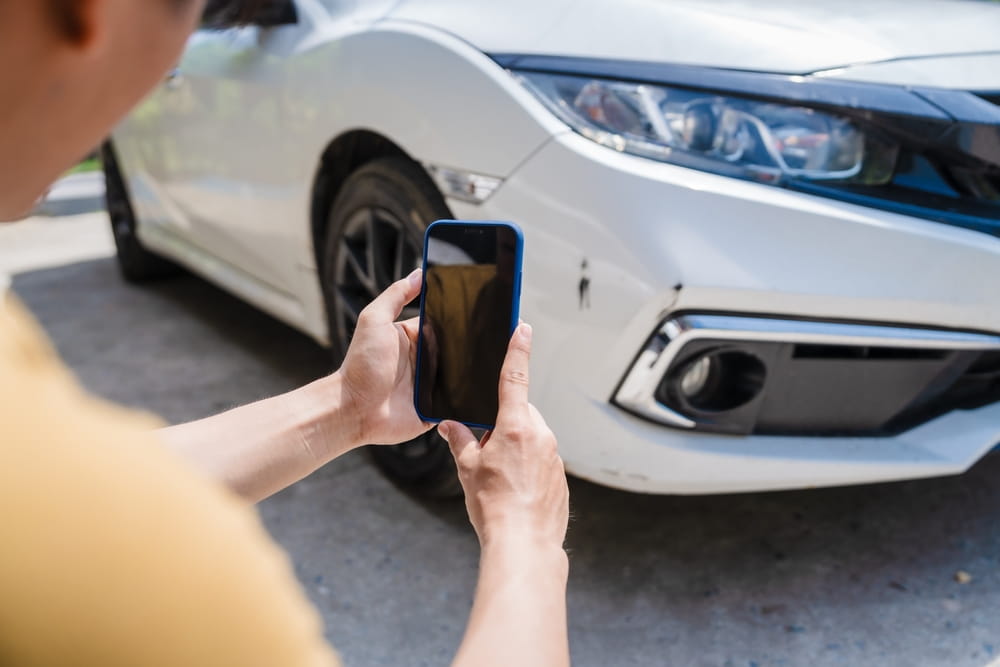Driver photographing vehicle damage after California car accident