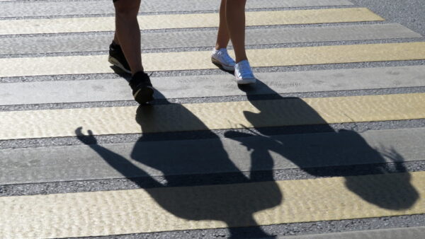 Two pedestrians crossing a marked crosswalk in San Jose, where California Vehicle Code Section 21950 requires drivers to yield the right of way