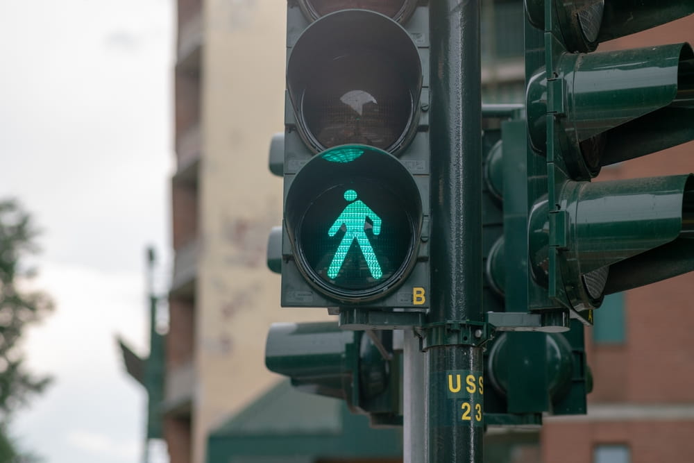 Pedestrian walk signal displaying green at a San Jose intersection, where a malfunctioning or mistimed signal can establish government liability under California law