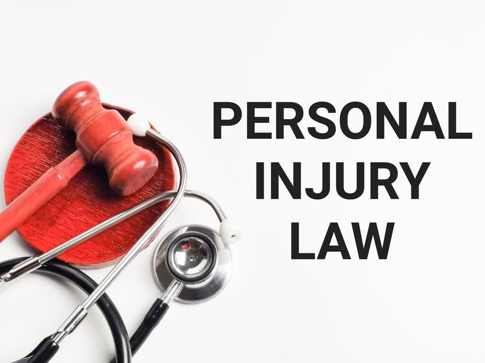 In a conceptual image blending medical and legal themes, "PERSONAL INJURY LAW" is written on a white background with a gavel and stethoscope, the focus being selective.






