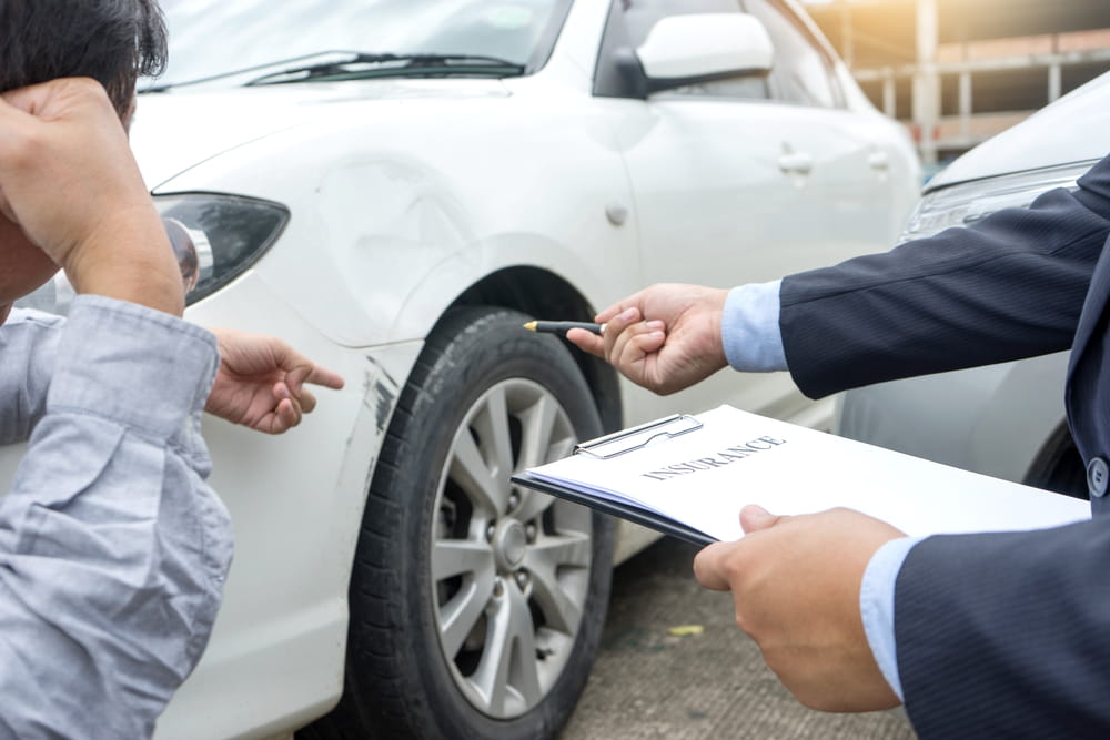 Insurance adjuster reviewing car damage after accident involving uninsured driver in San Jose
