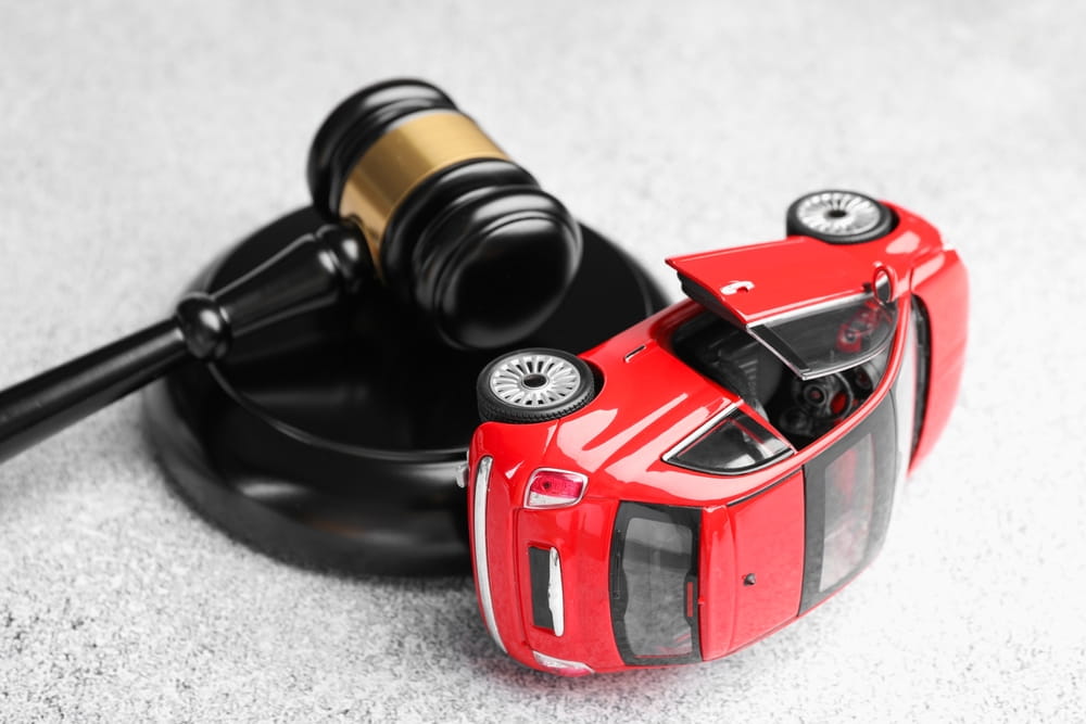 Gavel next to overturned toy car symbolizing wrongful death car accident lawsuit in San Jose