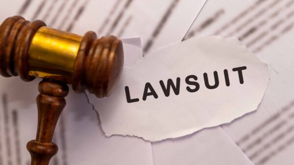 Judge’s gavel beside torn paper with the word lawsuit representing legal action or court case.