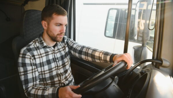 Commercial truck driver behind the wheel, whose speed, braking, and driving behavior are continuously recorded by the truck's electronic control module